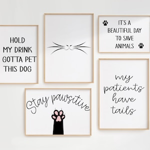 May include: Set of five black and white printable wall art prints with dog-themed quotes. The prints feature the text "Hold my drink I gotta pet this dog", "Stay pawsitive", "It's a beautiful day to save animals", and "My patients have tails".