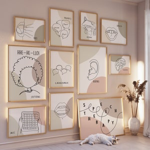 Op de afbeelding: Een set van 10 minimalistische lijnkunstprints met gouden frames, met illustraties van de menselijke anatomie met betrekking tot spraak en gehoor. De prints bevatten tekst zoals "Logopedie", "Gehoor", "Taal", "Stotteren", "Stem", "Articulatie", "Pragmatiek", "Auditief" en "Begrip".