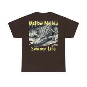 May include: A brown t-shirt with a graphic of an alligator in a swamp. The text "Mellow Mellow Swamp Life" is printed in yellow on the shirt.