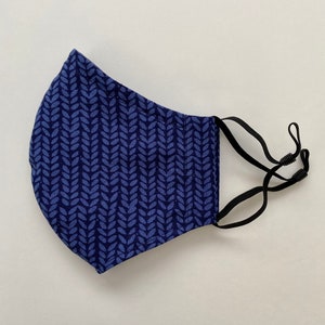 May include: A blue face mask with a white leaf pattern. The mask has black elastic ear loops.