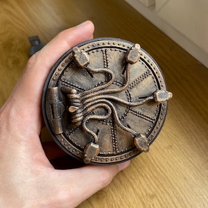 Peut inclure: Un objet circulaire de couleur bronze avec un design mécanique détaillé. L'objet présente des sections surélevées et rivetées et des éléments incurvés en forme de tube. Il a une esthétique steampunk.