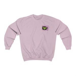 Op de afbeelding: Een lichtroze sweatshirt met lange mouwen. Een kleine afbeelding van een roze televisie met de tekst "I Fall Asleep To Forensic Files" staat op de linkerbovenborst. De sweatshirt is gemaakt van een zacht materiaal.