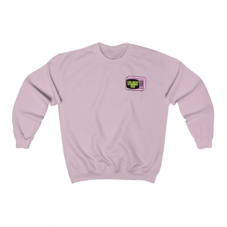 Op de afbeelding: Een lichtroze sweatshirt met lange mouwen. Een kleine afbeelding van een roze televisie met de tekst "I Fall Asleep To Forensic Files" staat op de linkerbovenborst. De sweatshirt is gemaakt van een zacht materiaal.