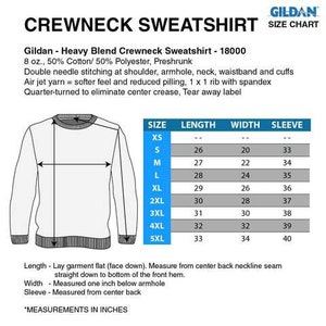 Op de afbeelding: Een witte crewneck sweatshirt met een maattabel. De tabel toont afmetingen in inches voor maten XS tot 5XL. De sweatshirt is gemaakt van een katoen- en polyestermix en heeft dubbele stiksels.