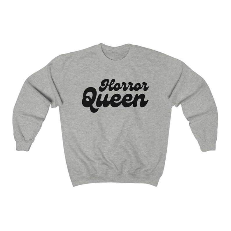 Może przedstawiać: Jasnoszara bluza z napisem "Horror Queen" w czarnym, retro kroju pisma. Bluza ma okrągły dekolt i długie rękawy. Tekst jest wyśrodkowany na klatce piersiowej.