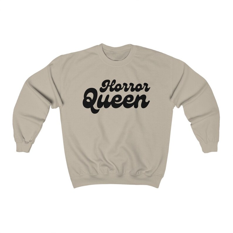 Może przedstawiać: Beżowa bluza z napisem "Horror Queen" w czarnym, retro kroju pisma. Odzież ma okrągły dekolt i długie rękawy. Tekst jest wyśrodkowany na piersi.