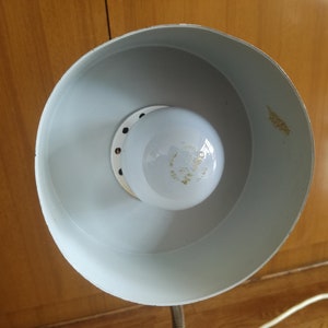 May include: A white lampshade with a white light bulb inside. The lampshade has a round shape and a smooth surface.