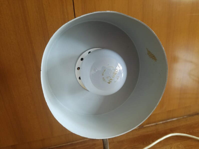 May include: A white lampshade with a white light bulb inside. The lampshade has a round shape and a smooth surface.
