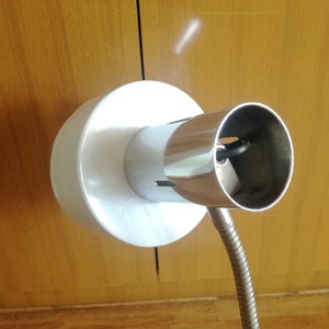 May include: A white and chrome adjustable lamp with a flexible arm. The lamp has a standard light bulb socket.