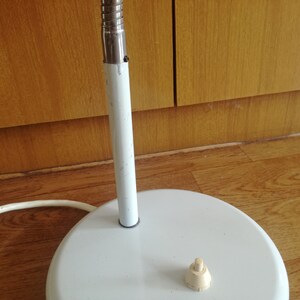 May include: White metal floor lamp with a white cord and a white on/off switch on the base.