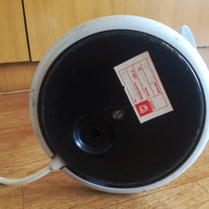 May include: The bottom of a white and black lamp with a round base. The lamp has a cord and a sticker that says "BETTRIST" and "MADE IN ITALY".