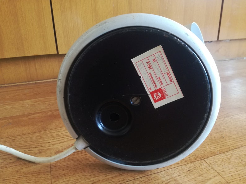 May include: The bottom of a white and black lamp with a round base. The lamp has a cord and a sticker that says "BETTRIST" and "MADE IN ITALY".
