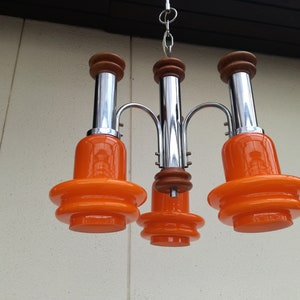Puede incluir: Una l&aacute;mpara de ara&ntilde;a moderna de mediados de siglo en cromo y naranja con cinco luces.