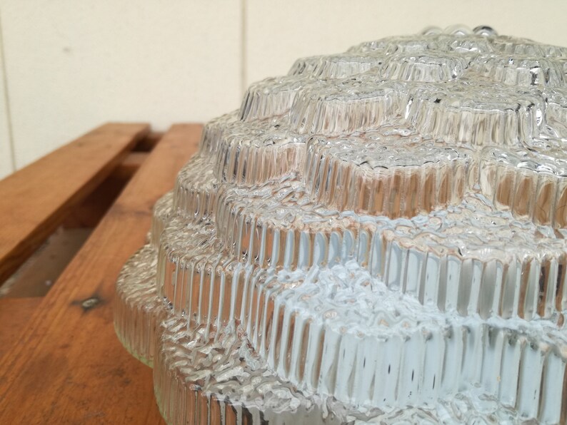 May include: A clear glass lampshade with a textured, geometric design. The shade is made up of multiple layers of glass, each with a different pattern.