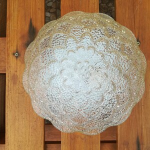 May include: A clear glass ceiling light fixture with a textured, flower-shaped design.
