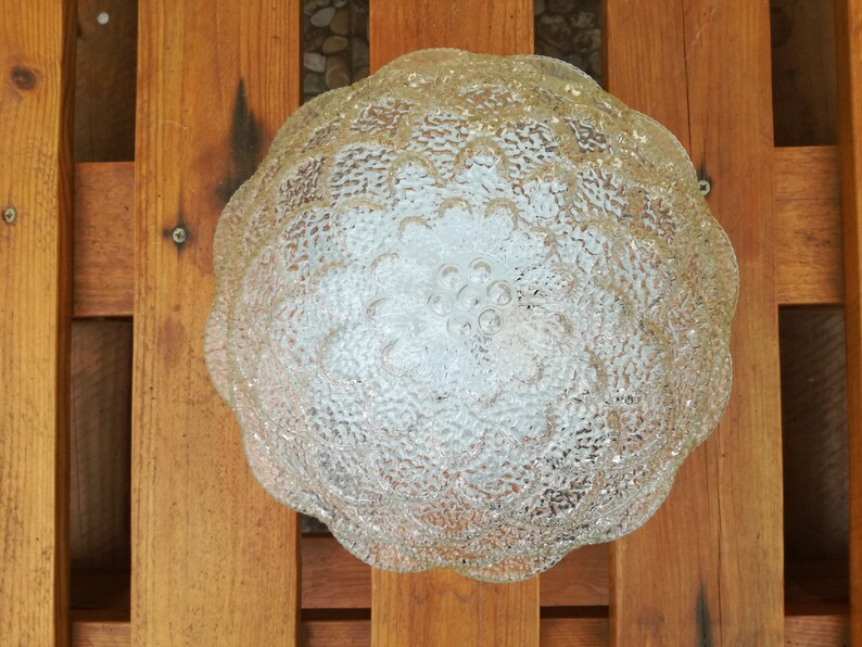 May include: A clear glass ceiling light fixture with a textured, flower-shaped design.