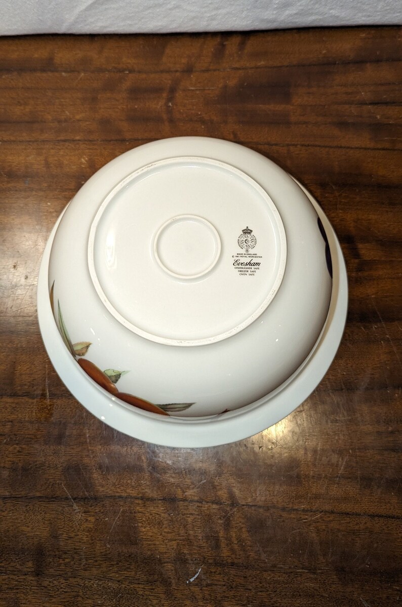 K&ouml;nnte beinhalten: Wei&szlig;e Keramiksch&uuml;ssel mit Blumenmuster und goldfarbenem Rand. Auf der Unterseite der Sch&uuml;ssel befindet sich ein goldenes Logo mit der Aufschrift "Evesham, Staffordshire, Made in England, Fine China".