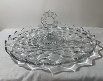 May include: A clear glass serving tray with a scalloped edge and a diamond pattern. The tray has a handle in the centre.