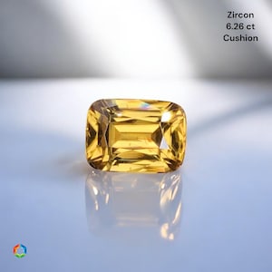 May include: A cushion-cut yellow zircon gemstone weighing 6.26 ct. The faceted stone displays a bright golden hue with internal light reflections and is positioned to show its clear, reflective surface and geometric cut.