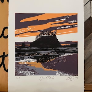 May include: A woodblock print of a sunset over a rocky beach with the text "Second Beach" and the artist's signature and date "Mark 25". The print is numbered 9/15.
