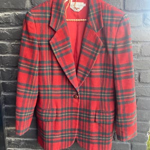 May include: A red, green and yellow plaid blazer with a single button fastening. The blazer is made from a soft, wool-like fabric.