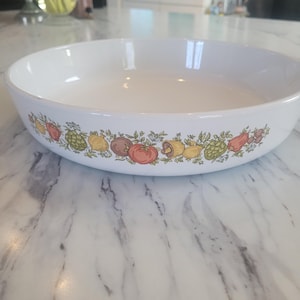 May include: White ceramic baking dish with a green, yellow and red vegetable design around the rim.