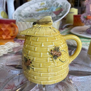 May include: A set of three ceramic mugs with a colourful rainbow design. Each mug features a different colour: red, orange, and yellow. The mugs have a glossy finish and a simple, modern shape. Ideal for tea or coffee.