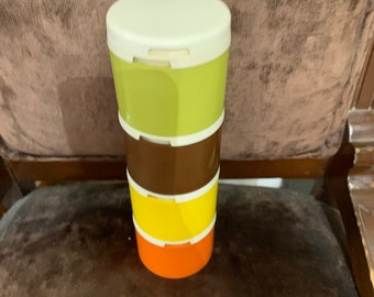 May include: A set of four stackable containers with lids. The containers are green, brown, yellow, and orange. The lids are white.