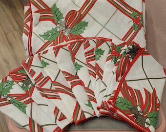 May include: A set of 10 red and green Christmas napkins with a festive design featuring holly and bells. The napkins are made of a white fabric with a red and green trim.