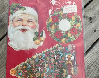 May include: A package of Hang-Up Prints containing 7 Christmas decorations. The red packaging features a Santa Claus face, a wreath with a Season's Greetings tag, and a decorated Christmas tree with various ornaments and toys printed on the sheet.