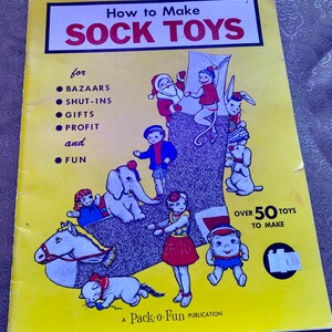 May include: A vintage yellow book titled "How to Make Sock Toys" with illustrations of sock toy characters. The book cover includes text for bazaars, gifts, profit, and fun. The book is a Pack-o-Fun publication.