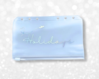 May include: A light blue plastic zippered pouch with a holographic design that says "Holidays" with a plane and heart graphic.