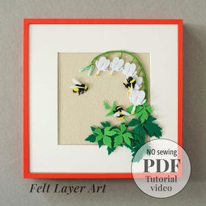 May include: A square framed artwork featuring layered felt craft depicting white bleeding heart flowers, green leaves, and three black and yellow bumblebees. The text "Felt Layer Art" and "NO sewing PDF Tutorial video" is visible on the image.