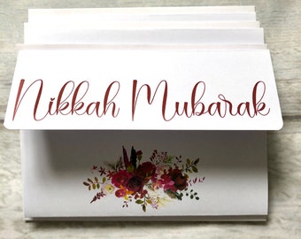 Puede incluir: Tarjeta blanca con el texto "Nikkah Mubarak" en escritura burdeos. La tarjeta está decorada con un diseño floral burdeos.