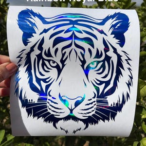 May include: A decal featuring a tiger head graphic with a holographic rainbow royal blue finish on a white backing. The design displays intricate black and blue striped patterns and the text Rainbow Royal Blue at the top of the sheet.