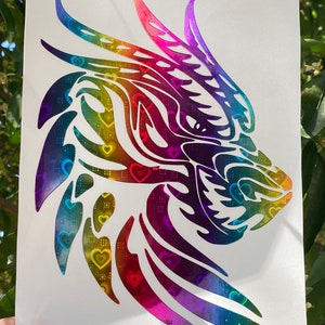 K&ouml;nnte beinhalten: Ein regenbogenfarbener, schimmernder Vinyl-Aufkleber mit einem Drachenkopf vor einem Hintergrund mit Herz-Muster.