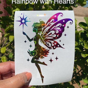 May include: A holographic sticker featuring a fairy with rainbow accents and heart details. The fairy is holding a star wand. The sticker has the text "Rainbow with Hearts" at the top.