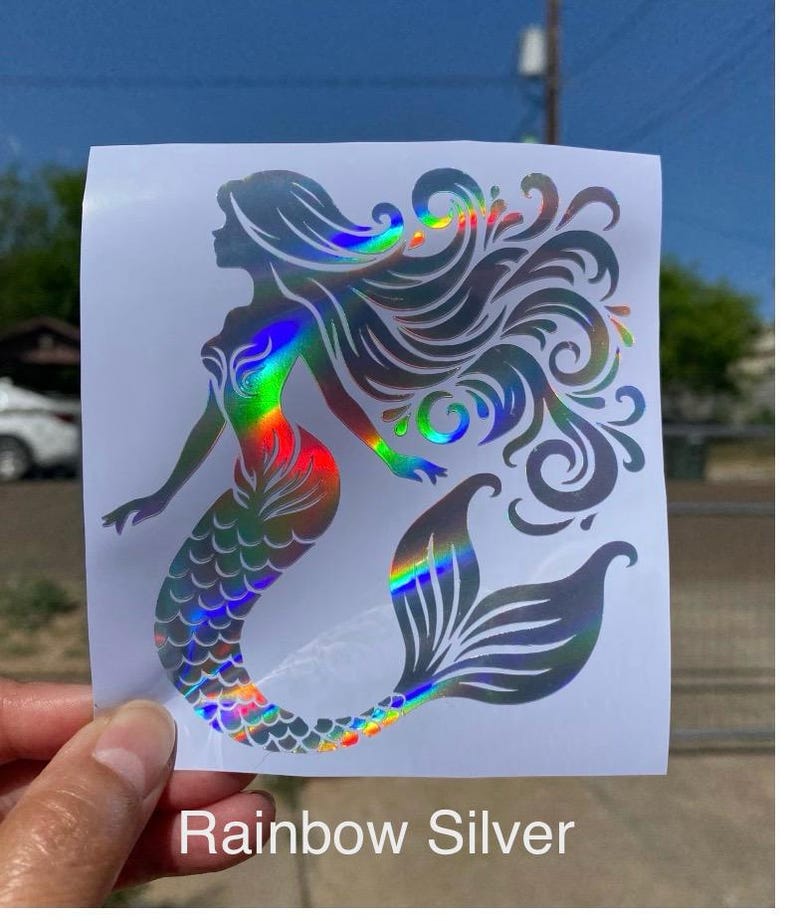 K&ouml;nnte beinhalten: Ein holografischer Meerjungfrau-Aufkleber mit Regenbogeneffekt. Die Meerjungfrau hat flie&szlig;endes Haar und einen detaillierten Schwanz. Der Text "Rainbow Silver" ist unten auf dem Aufkleber aufgedruckt.