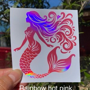 K&ouml;nnte beinhalten: Ein Sticker mit einer pinkfarbenen Meerjungfrau mit einem holografischen Regenbogen-Schwanz und -Haar. Die Meerjungfrau ist eine Silhouette mit flie&szlig;endem Haar und einem detaillierten Schwanz. Der Text "Rainbow hot pink" steht unten.