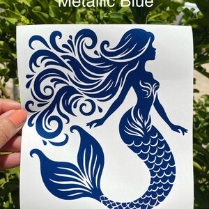 K&ouml;nnte beinhalten: Ein metallisch-blauer Meerjungfrau-Aufkleber mit flie&szlig;endem Haar und einem detaillierten Schwanz. Der Text "Metallic Blue" wird oben angezeigt. Das Meerjungfrau-Design befindet sich auf wei&szlig;em Hintergrund.