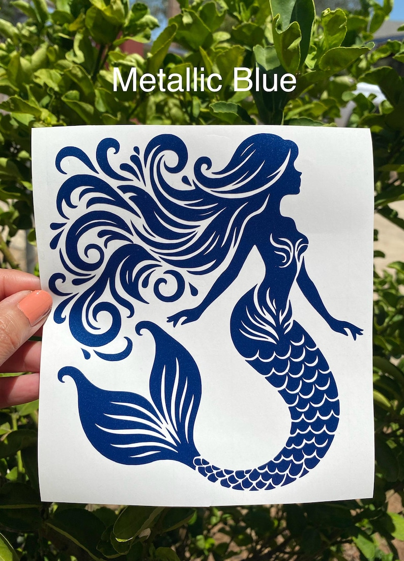 K&ouml;nnte beinhalten: Ein metallisch-blauer Meerjungfrau-Aufkleber mit flie&szlig;endem Haar und einem detaillierten Schwanz. Der Text "Metallic Blue" wird oben angezeigt. Das Meerjungfrau-Design befindet sich auf wei&szlig;em Hintergrund.