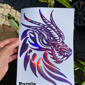K&ouml;nnte beinhalten: Ein violetter, schimmernder Vinyl-Aufkleber mit einem Drachenkopf mit filigranen Details. Der Aufkleber befindet sich auf einem wei&szlig;en Hintergrund und das Wort "Purple" steht unter dem Drachen.