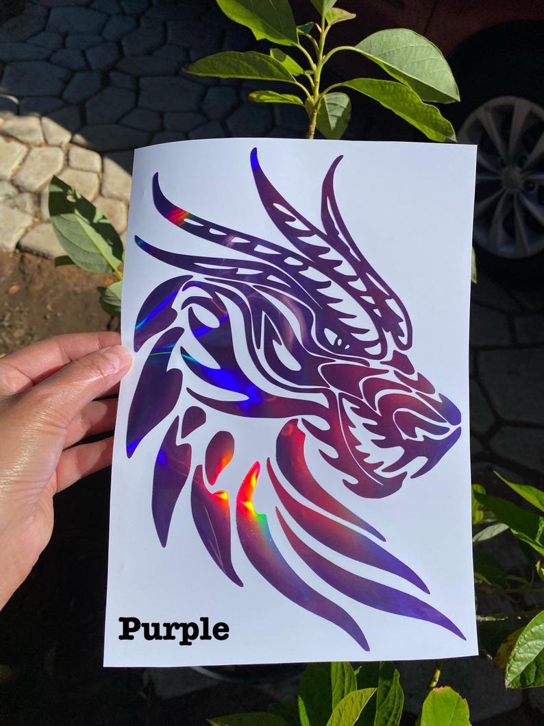 K&ouml;nnte beinhalten: Ein violetter, schimmernder Vinyl-Aufkleber mit einem Drachenkopf mit filigranen Details. Der Aufkleber befindet sich auf einem wei&szlig;en Hintergrund und das Wort "Purple" steht unter dem Drachen.