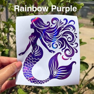 K&ouml;nnte beinhalten: Ein violetter Meerjungfrau-Aufkleber mit schillernden Highlights. Der Aufkleber zeigt eine Meerjungfrau-Silhouette mit flie&szlig;endem Haar und einem detaillierten Schwanz. Der Text "Rainbow Purple" wird &uuml;ber dem Aufkleber angezeigt.