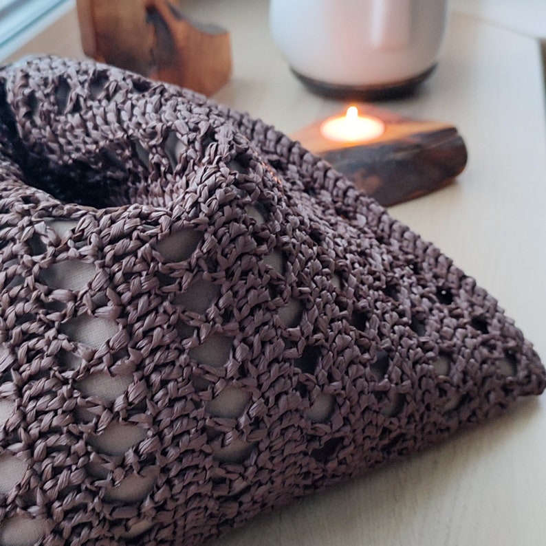 a crocheted pillow sitting on a table next to a potted plant