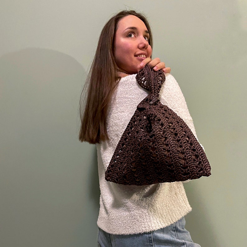 a woman leaning against a wall holding a purse