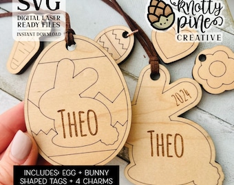 Puede incluir: Etiquetas de madera en forma de huevo de Pascua y conejo con el nombre "THEO" y el año "2024" grabados. Las etiquetas son marrones y tienen un acabado de madera natural. Vienen con cuatro encantos: una zanahoria, un huevo, una flor y un corazón.