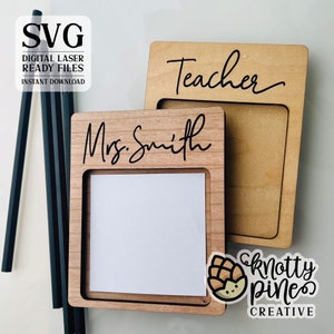 Pu&ograve; includere: Due blocchi appunti in legno con una fessura per note adesive. Il blocco appunti a sinistra dice "Mrs. Smith" e quello a destra dice "Teacher".