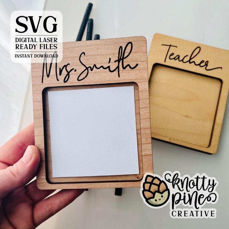 Pu&ograve; includere: Due porta note in legno con un ritaglio per un post-it. Un porta note ha il testo "Mrs. Smith" inciso su di esso, e l'altro ha il testo "Teacher" inciso su di esso.
