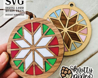 May include: Two wooden Christmas ornaments with a snowflake design. One ornament is red, green, and white, and the other is brown, pink, and blue. The ornaments are laser cut and ready to be painted or stained.